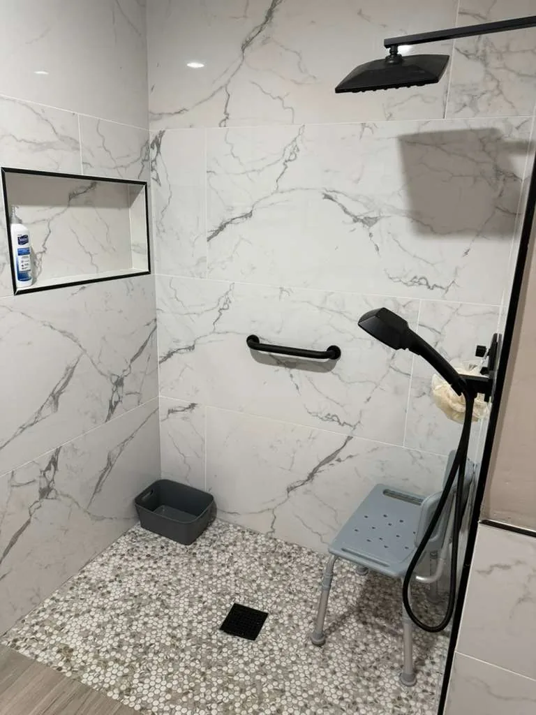 Walk-in shower with grab bar, handheld shower and shower chair.